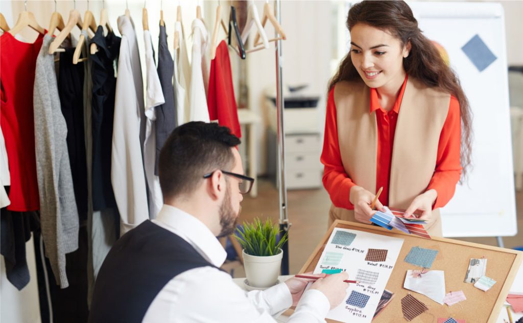 Two people are working in the clothing store and discussing the clothing manufacturer