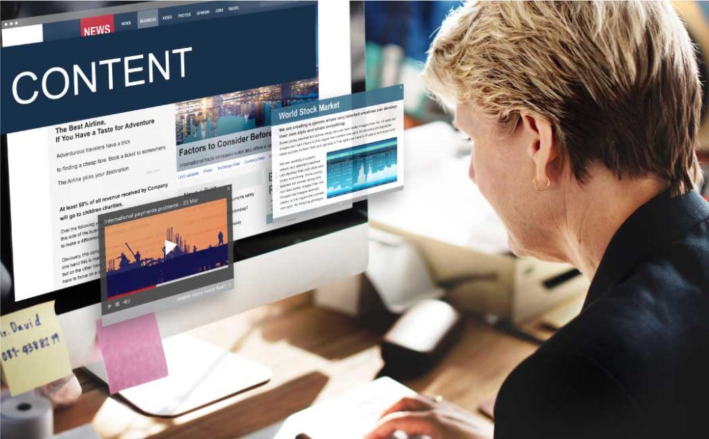 A person working at a desk with a computer monitor displaying articles