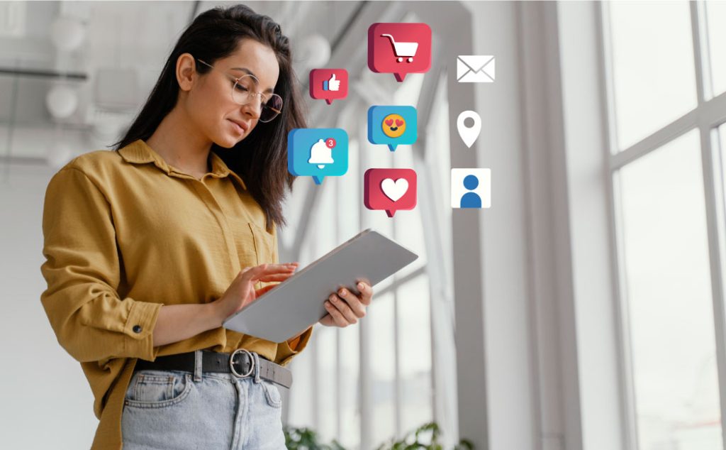 A woman holding a tablet with social media icons floating around her