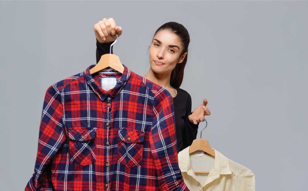 A person holding up two shirts on hangers