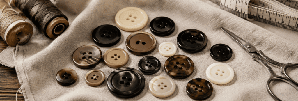 Assorted flat sew-through buttons in black, beige, brown, and cream colors.