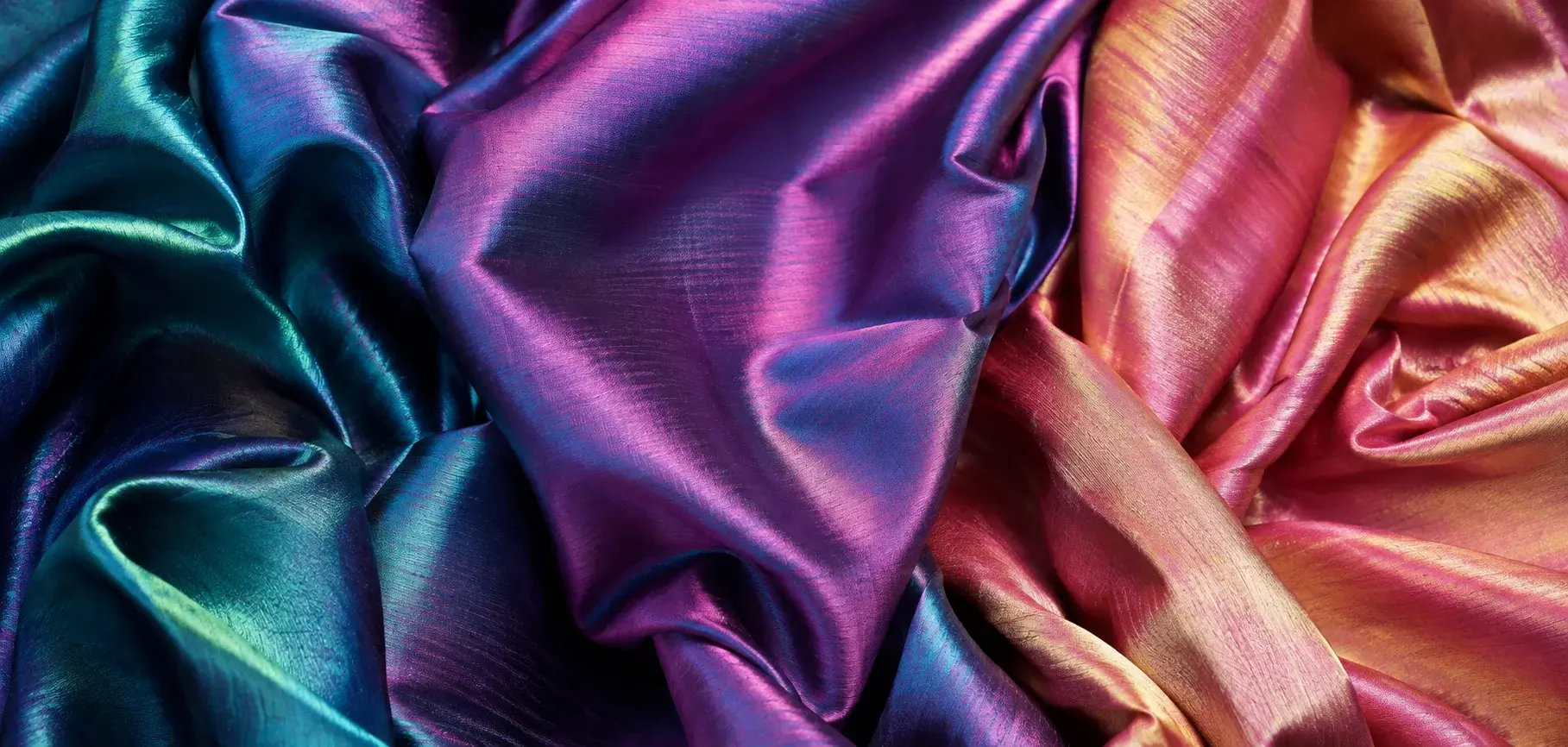 Iridescent shot silk taffeta fabrics in teal, purple, pink, and gold with a rich color-changing sheen.