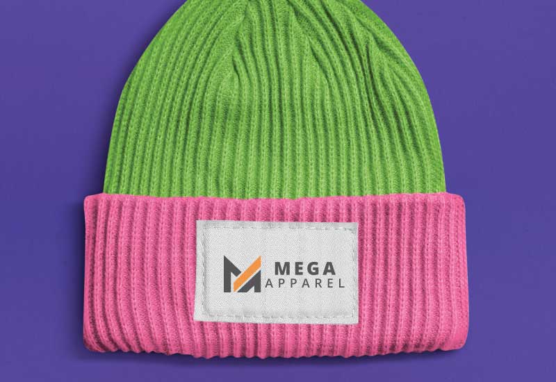 A close-up photo of a knitted beanie in shades of green and pink with the Mega Apparel logo