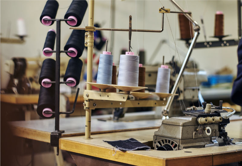 A sewing machine with spools of thread sits on a wooden table