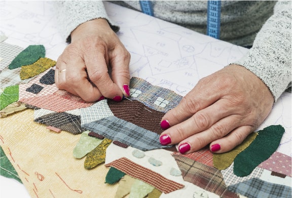 A woman is sewing a quilt on a table