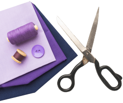 A pair of scissors, a spool of purple thread, a purple button, and a purple envelope