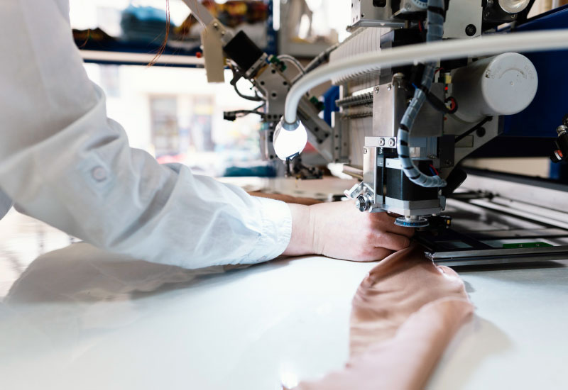  A close-up view of someone in a white coat operating an industrial sewing machine