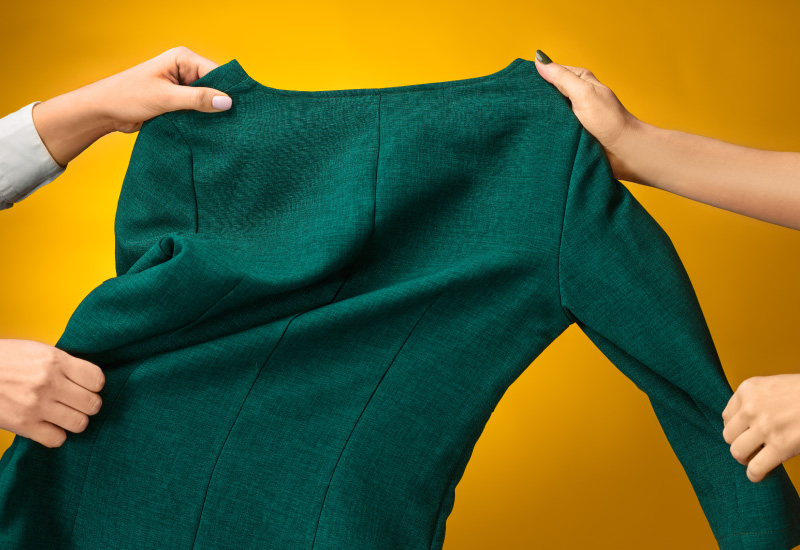 Shows two hands, one on each side, stretching a piece of green custom clothing product