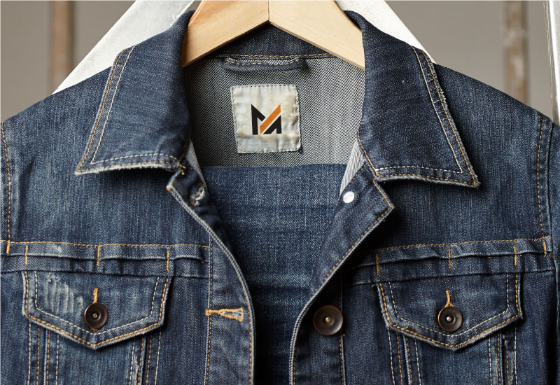  A denim jacket on a hanger with the logo of Mega Apparel